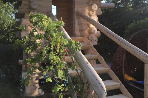 Ein hochwertiges Spielhaus mit Schaukel im umzäunten Garten sorgt für leuchtende Kinderaugen